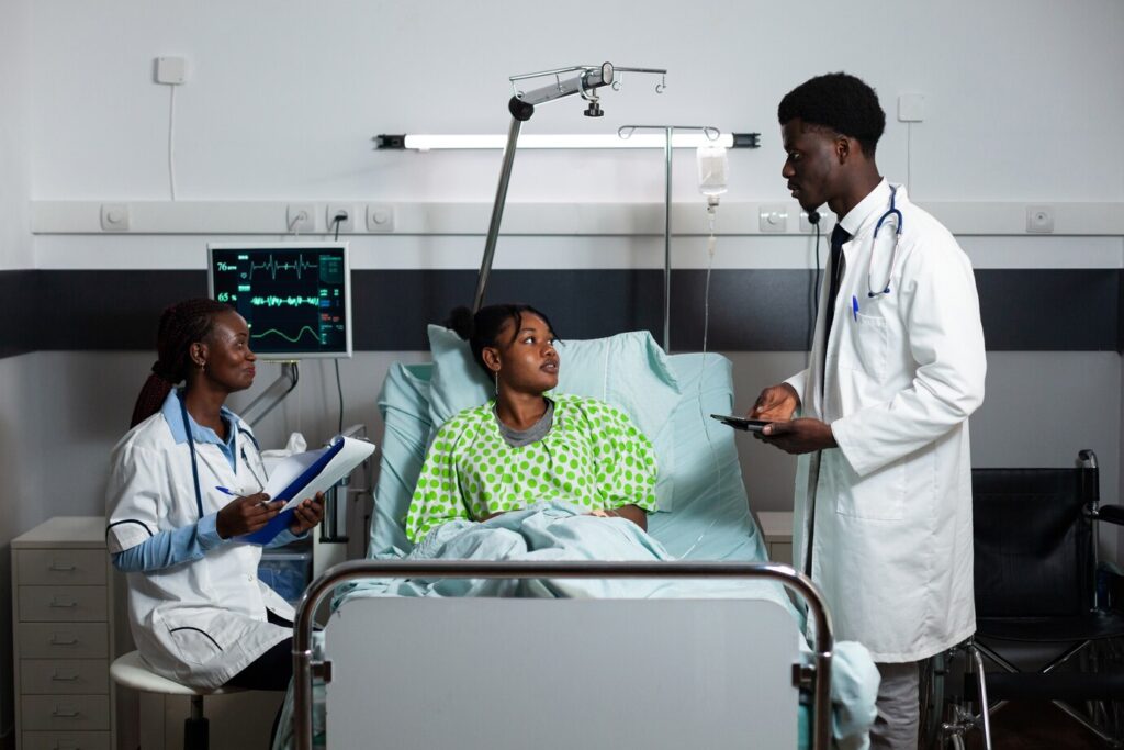 Afro doctors consulting a young adult in a hospital ward - Holistic Care Medicals